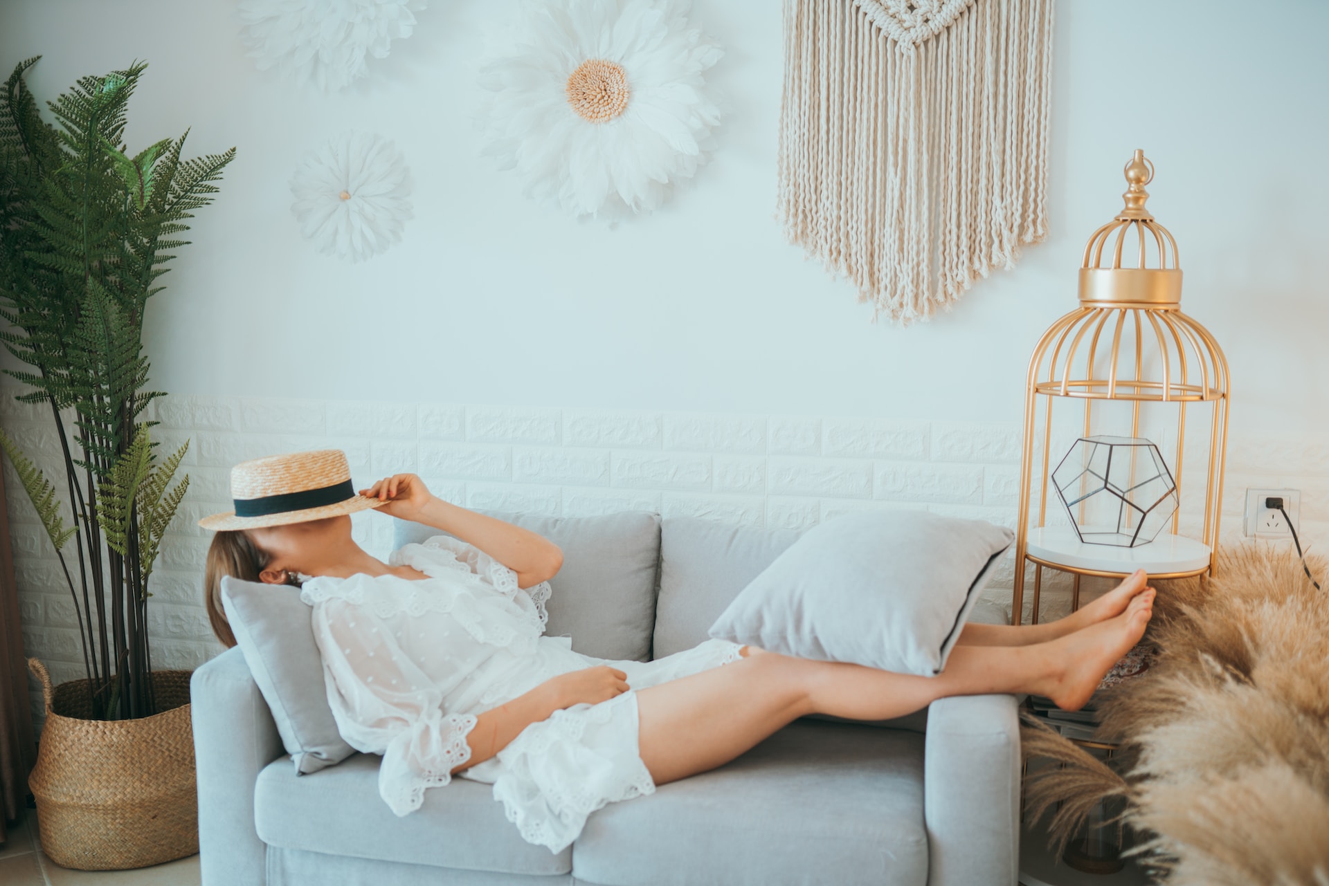 woman lying on loveseat with hat covering face